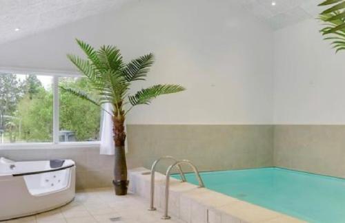 a pool with a palm tree and a bath tub at Pool activity house for 14 people in Bøtø By