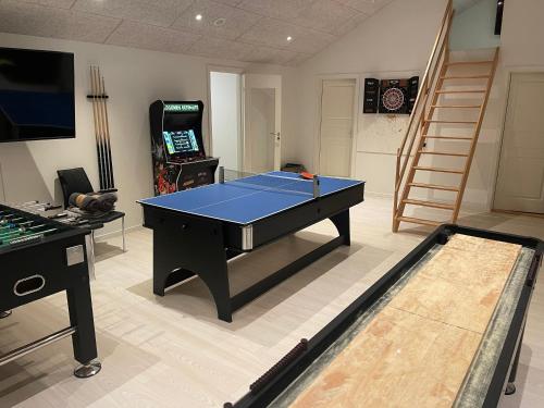 a room with a ping pong table and a video game at Pool activity house for 14 people in Bøtø By