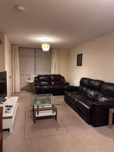 Una sala de estar con un sofá de cuero y una mesa de café. en Hanham Lodge, en Longwell Green