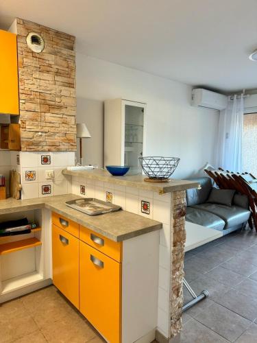 une cuisine avec des placards orange et blancs et un canapé dans l'établissement Appart résidence avec piscine, à Propriano