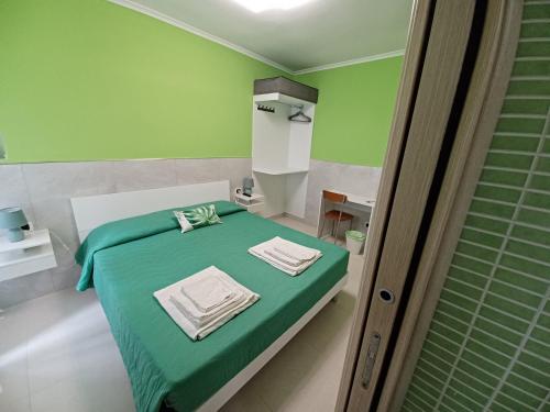 ein grünes Schlafzimmer mit einem Bett mit Handtüchern darauf in der Unterkunft B&B Quattro Palazzi Napoli Centro in Neapel