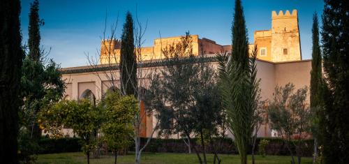 a building with a castle in the background with trees at Riad Sougtani in Marrakech