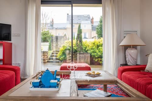 Elle comprend un salon doté d'un mobilier rouge et d'une grande fenêtre. dans l'établissement Cocon Urbain au coeur du Mans - Parking & Jardin - L'Instant Clef, au Mans
