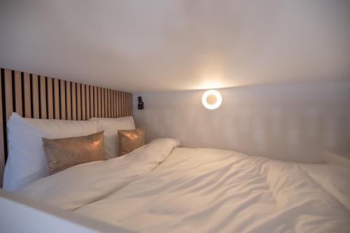 un lit avec des draps blancs et des oreillers dans une chambre dans l'établissement CIA - Mezzanine Studio by Arc de Triomphe, à Paris