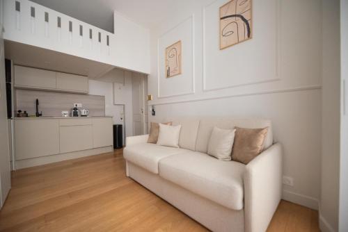 - un canapé blanc dans un salon avec une cuisine dans l'établissement CIA - Mezzanine Studio by Arc de Triomphe, à Paris