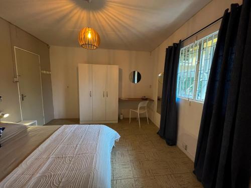 a bedroom with a bed and a desk and a window at Villa Le Guètali in Pointe d'Esny