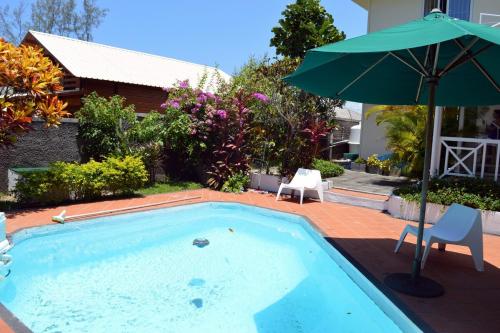 a swimming pool with an umbrella and two chairs and a table at Villa Le Guètali in Pointe d'Esny