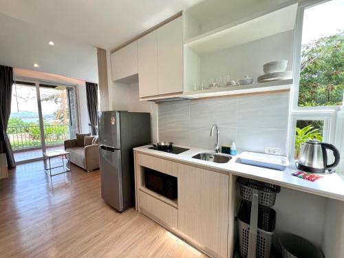 a kitchen with a refrigerator and a sink in it at Beachfront Bliss at Naiyang Phuket by ALPHATEL in Phuket