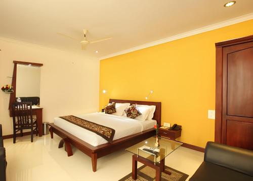 a bedroom with a bed and a yellow wall at Hotel Pearl Palace in Cochin
