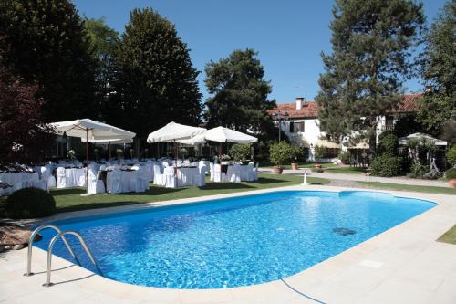 a swimming pool with tables and white umbrellas at Villa Casa Country in Bovolenta