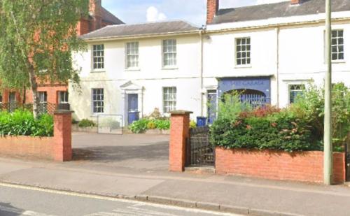 a white house with a gate in front of a street at Historic Manor house sleeps 10, free parking in Oxford