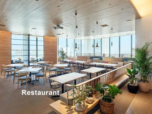 a restaurant with tables and chairs and windows at Mitsui Garden Hotel Yokohama Minatomirai Premier in Yokohama