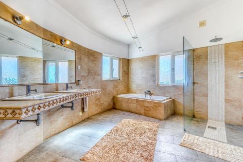 a bathroom with two sinks and a tub and a shower at Vila Paraiso - Amazing villa in Carvoeiro