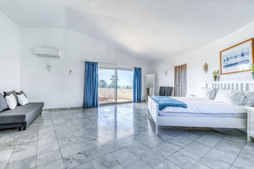 a bedroom with a bed and a couch and a window at Vila Paraiso - Amazing villa in Carvoeiro
