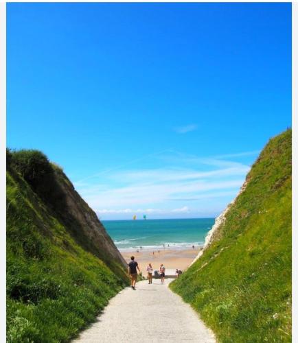 un groupe de personnes marchant sur un chemin en direction de la plage dans l'établissement L entre deux, à Sangatte