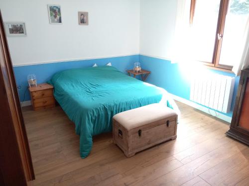 1 dormitorio con 1 cama con manta verde y taburete en Maison familiale dans le golfe du Morbihan, en Saint-Avé