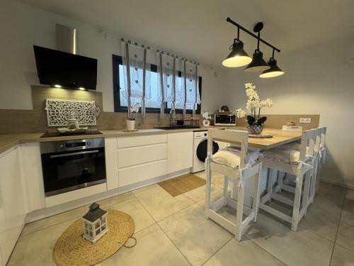 une cuisine avec des armoires blanches et une table avec des chaises dans l'établissement Le Refuge - Confort - 5 pers - Rêve au Mans, à Ruaudin