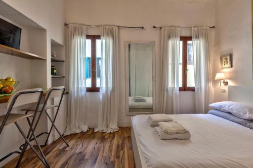 a bedroom with a bed with two chairs and a mirror at Santo Spirito Suite in Florence