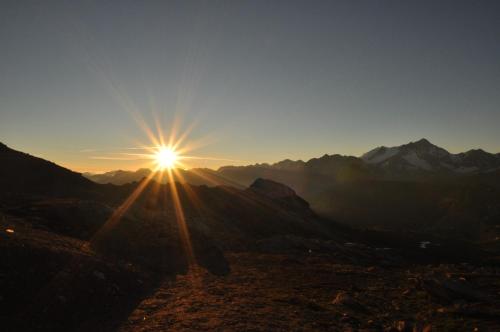 a sun is setting over a mountain range at Hôtel Hermitage in Evolène