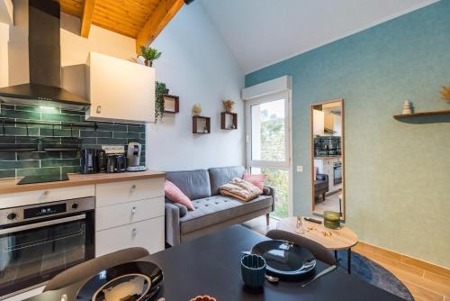 a kitchen and living room with a couch and a table at NEW Le Turquoise au coeur de Guingamp Parking in Guingamp