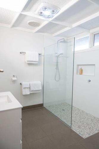 a bathroom with a glass shower and a sink at Metung Holiday House in Metung