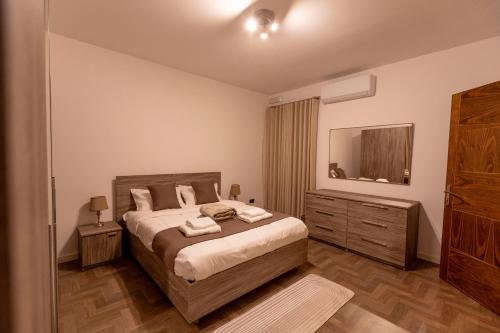 a bedroom with a bed with a dresser and a mirror at Galileo - Sliema Seafront Luxury Apartment in Sliema