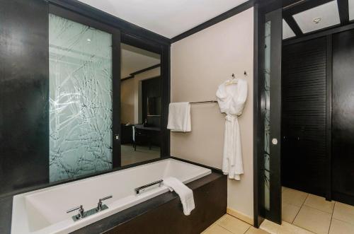 a bathroom with a bath tub and a mirror at Zimbali condo family room 10 in KwaDukuza
