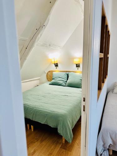 - une chambre mansardée avec un lit vert dans l'établissement L'Attic, appartement au cœur de Cancale, à Cancale