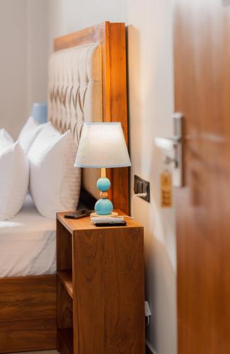 a lamp on a table next to a bed at Ivory Resort Dikwella in Dickwella