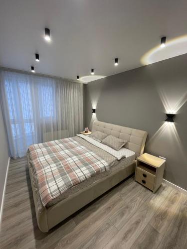 a bedroom with a large bed and a night stand at Buiucani Residence in Chişinău