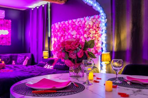 une chambre violette avec une table et un vase de fleurs dans l'établissement Sweet Dreams Jacuzzi, à Le Breuil