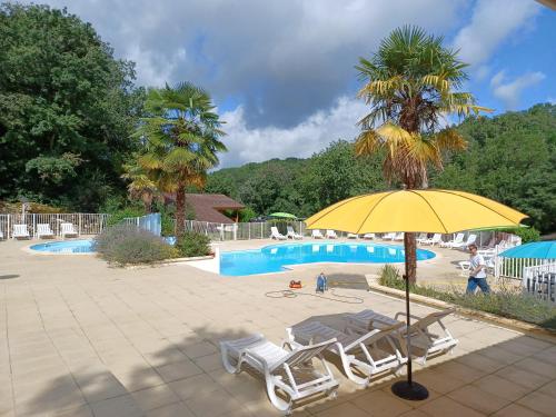 - un parasol jaune et des chaises longues à côté de la piscine dans l'établissement Chalet Lot, à Mauroux