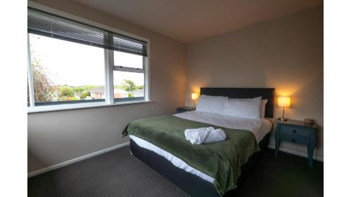 a bedroom with a bed and two windows at 3-bedroom 2-bathroom Bright & Sunny Family home in Auckland