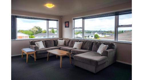 a living room with a couch and two windows at 3-bedroom 2-bathroom Bright & Sunny Family home in Auckland