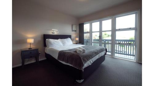 a bedroom with a large bed and a balcony at 3-bedroom 2-bathroom Bright & Sunny Family home in Auckland