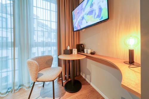 a room with a table and a tv and a chair at INA Boutique Hannover-Linden - Digital Access in Hannover