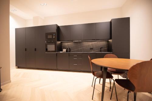 une cuisine avec des armoires noires et une table en bois dans l'établissement CIA - Marguerite de Rochechouart, à Paris