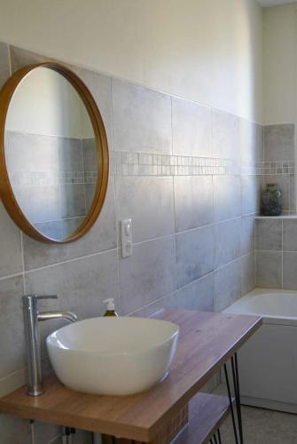 une salle de bain avec un lavabo, un miroir et une baignoire dans l'établissement La Marie-Louise, à Brive-la-Gaillarde