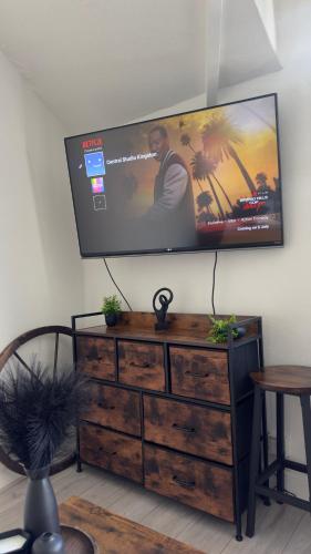 a flat screen tv on a wall above a dresser at Free Parking! Kingston Studio, ideal for professionals relocators and leisure stays, near Kingston Station and Shopping Centre in Kingston upon Thames