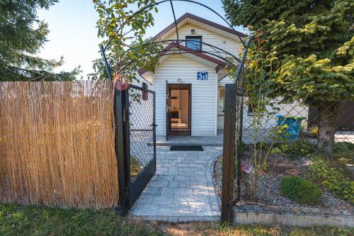 a gate in front of a white house at Tonkielek - Domek z Jacuzzi Nad Rzeką Bug in Tonkiele