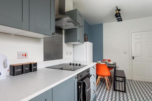 een keuken met witte kasten en een oranje stoel bij Modern 4-Bed Home Sleeps 6 in Stockton-on-Tees