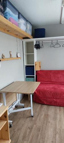 a room with a table and a red bed at Studio fonctionnel 16m2 avec vue panoramique in Puy-Saint-Vincent