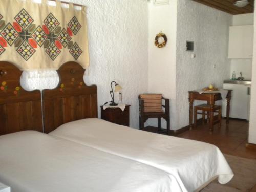 a bedroom with a white bed and a table at Agrampeli in Megalo Chorio