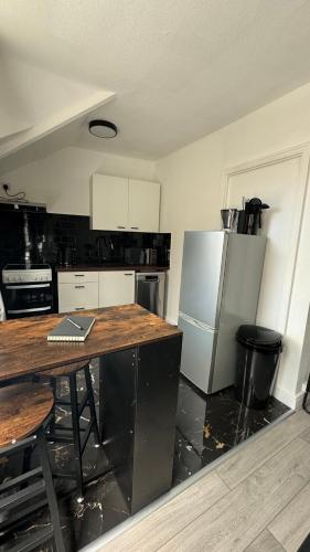 a kitchen with a table and a refrigerator at Free Parking! Kingston Studio, ideal for professionals relocators and leisure stays, near Kingston Station and Shopping Centre in Kingston upon Thames