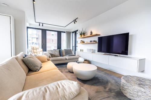 a living room with a couch and a flat screen tv at De Branding A21 in Cadzand