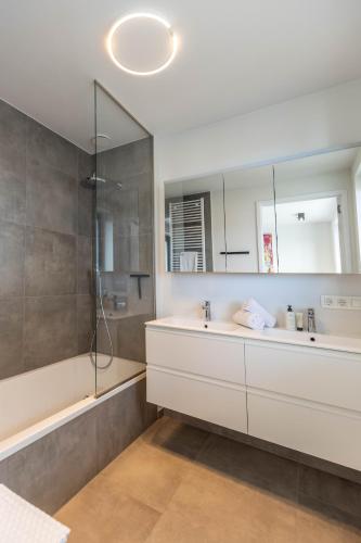 a bathroom with a tub and a sink and a mirror at De Branding A21 in Cadzand