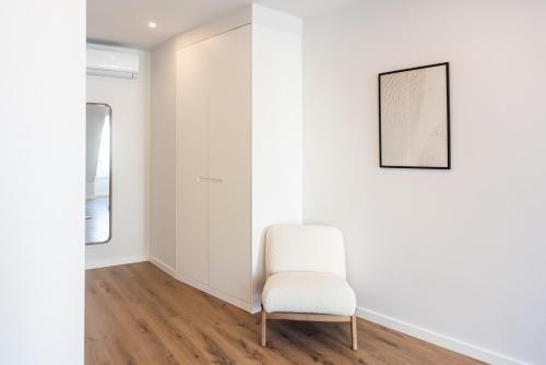 a white chair in a white room with a picture at The Haus - Santa Bárbara II in Lisbon