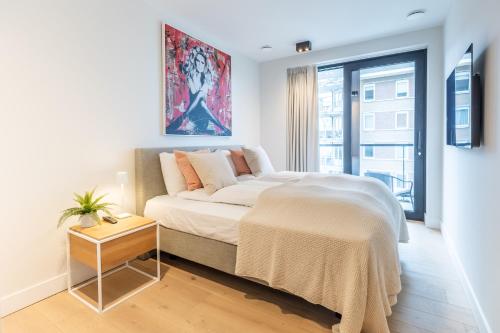 a white bedroom with a bed and a window at De Branding A21 in Cadzand