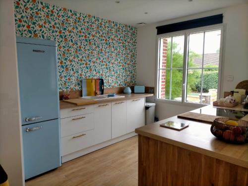 eine Küche mit weißen Schränken und einem blauen Kühlschrank in der Unterkunft Maison du petit p(a)in in Cucq