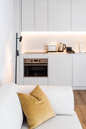 a white living room with a couch and a kitchen at The Haus - Santa Bárbara II in Lisbon
